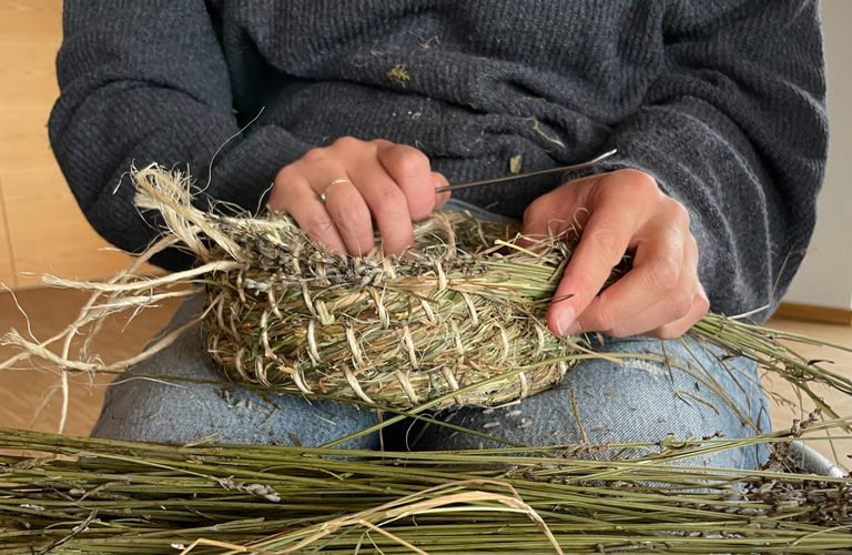 Bild von Händen, die einen Kräuterkorb am Schoß binden.